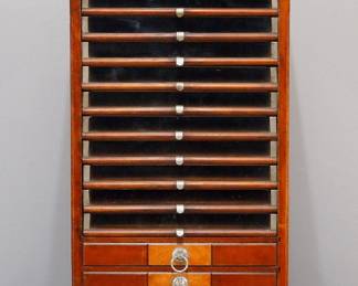 A turn of the century "Corticelli Silk" thread cabinet. Cherry construction features a scalloped crown over ten glass front drawers and thee with wood fronts and nickeled handles, mirrored end panels on a molded base.  Older finish with some wear.  18 1/2 x 16 1/2 x 36 1/2" high.  