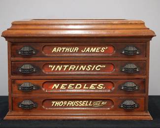A turn of the century Arthur James thread cabinet.  Walnut construction features a molded top with lift up panel over four drawers with reverse painted glass labels "Arthur James, Intrinsic, Needles, Thos Russell Sole Agt", original cast iron pulls and paneled ends.  Old finish with minor wear.  24 x 15 x 16" high.  