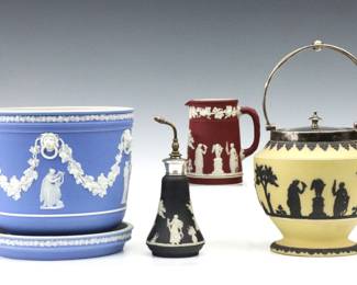 Four pieces of late 19th to early 20th century Wedgwood Jasperware.  Various color jasper dipped bodies with Classical figures and vintage garlands in White relief, includes a jardiniere with underplate, a biscuit jar with Silverplate lid and handle, a creamer and a perfume atomizer with Sterling Silver top.  Each marked "Wedgwood".  Minor surface wear, very minor losses to relief decoration, jardinière with chip at draining hole, perfume lacks elements.  Up to 7" diameter and 6 1/2" high not including handle.  