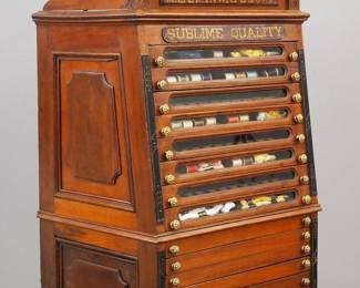 A late 19th century M. Heminway & Sons thread cabinet.  Walnut construction features a pediment crown and applied Burl Walnut panels reading "M. Heminway & Sons, Sublime Quality" over eight glass fronted drawers and six wooden drawers with Gold painted knobs and paneled ends.  Older finish with wear and minor damage, restored back panel.  23 x 15 x 36 3/4" high.  