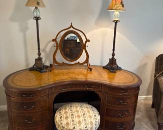 Maitland Smith Regency Style inlayed Mahogany oval partners desk with hand tooled leather writing surface.                                                                                                          28" H 63 1/2" W X 26" D                                                                  Ornate Candlestick lamps with glass orbs and silk shades. Round Louis style stool with fabric upolostery,