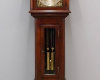 An early 20th century Waterbury grandfather clock.  8-day weight driven movement with hour and half hour chiming on one tubular bell, arched Brass dial with engraved filigree design, Silvered chapter ring with Arabic numerals, subsidiary seconds, painted upper dial with moon phases in a Starry sky.  Mahogany Chippendale style case features a hood with broken arch crest above an arched door frame flanked by molded corner columns, over a waist section with rectangular glass door and  paneled base with molded frame and cutout bracket feet.  Older with minor wear, running when cataloged.  93" high overall.  ESTIMATE $800-1,200