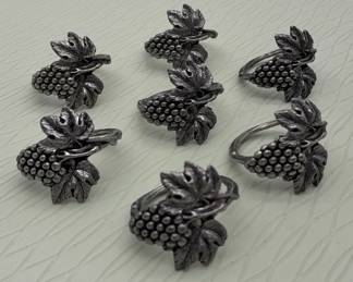 A set of seven vintage pewter napkin rings shaped like grape clusters.