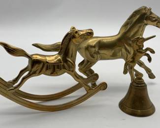 A vintage set of brass rocking horse, standing horse, and unicorn bell.
