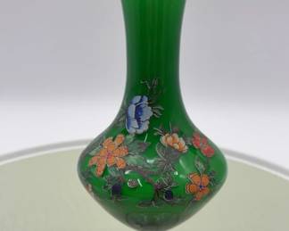 A handpainted emerald green glass vase with floral motifs and gold trim.