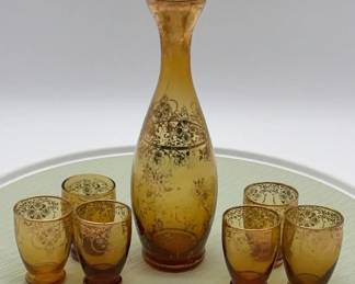 Amber glass decanter and six cordial glasses with gold floral overlay.