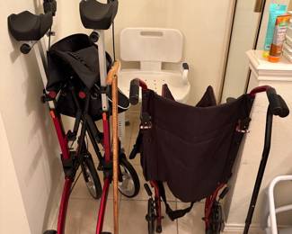Mobility Aids Collection: Red Rollator Walker, Burgundy Wheelchair, Carved Wooden Cane, and Black Quad Cane