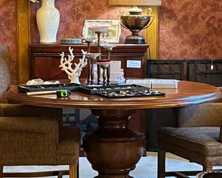 Beautiful solid wood pedestal round dining table with four upholstered dining chairs on casters.