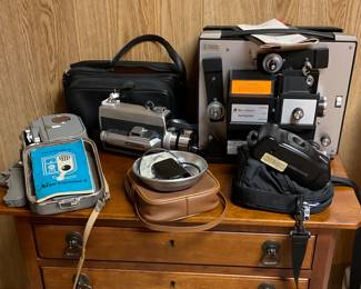 Vintage Filming and Photography Equipment Available Including a Belle & Howell "Monterey" 8mm Projector (With Original Manual), a Ricoh Shotmaster Tru-Zoom Camera and Carrying Case, a Honeywell Elmo Super 104 Movie Camera with Original Carrying Case, a Nizo Exposomat 8 Recorder and More!