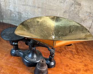 This lot features an antique Fairbanks cast iron balance scale with a brass scoop pan/hopper and a separate platform for weights (included). This scale (without hopper) measures, 9” H x 16” W x 5” D.

