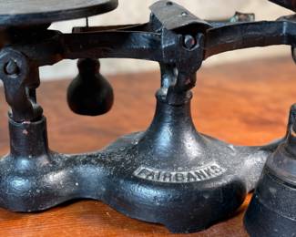This lot features an antique Fairbanks cast iron balance scale with a brass scoop pan/hopper and a separate platform for weights (included). This scale (without hopper) measures, 9” H x 16” W x 5” D.

