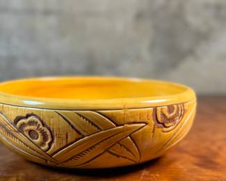This lot features an antique bowl by Weller Pottery in their "Paragon" pattern, dating to the late 1920s. This bowl measures, 3.25” H x 9.75” W x 9.75” D. The Paragon line, introduced in 1931, is known for its woodcut-like floral motif, which is consistent with the design on your bowl. There is one very small hairline crack shown in photos.

