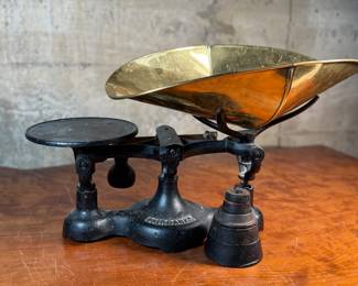 This lot features an antique Fairbanks cast iron balance scale with a brass scoop pan/hopper and a separate platform for weights (included). This scale (without hopper) measures, 9” H x 16” W x 5” D.

