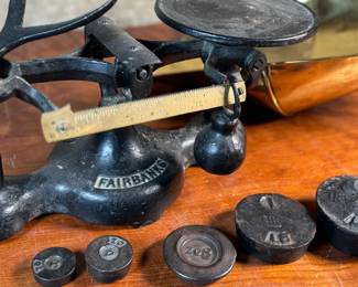 This lot features an antique Fairbanks cast iron balance scale with a brass scoop pan/hopper and a separate platform for weights (included). This scale (without hopper) measures, 9” H x 16” W x 5” D.

