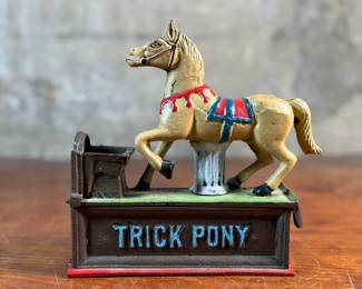 This lot features a reproduction cast iron mechanical bank known as the "Trick Pony". This bank measures, 7” H x 7” W x 2.5” D. The bank was originally patented in 1885 by Juleus Mueller, with manufacturing rights assigned to Charles and Walter Shepard. To operate the bank, a coin is placed in a small trough on the left, and a lever is pulled. 

