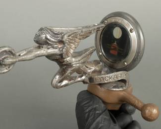 Boyce Motor Meter Goddess of Speed. Main piece is by Packard in block letters. Moto meters window shows a gold colored bi-plane. Has a brass colored dog bone base