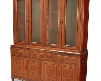 1310
An Indonesian mahogany china cabinet
20th century
En suite with dining table and chairs, the carved wood cabinet with brass inlaid borders and inset pulls, featuring an openwork cornice depicting grapes and leaves, the upper console comprising four glazed cabinet doors revealing two glass shelves, the lower console with pull-out surface above three flatware service drawers lined in felt, above four cabinet doors with conforming carved motifs, revealing a single shelf to each side, raised on ball-in-claw feet
84" H x 66" W x 19.25" D
Estimate: $150 - $250