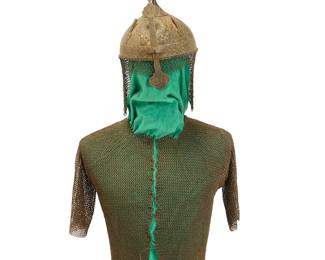 1122
An Islamic 'Turban' helmet and chain mail shirt
18th/19th century
Comprising a short-sleeved chain mail shirt together with a 'Khula Khud'-style spiked helmet with nose guard, two plume holders and a chain mail neck guard or 'aventail' attached to the helmet edge, the helmet decorated with elaborate chased floral arabesque designs and borders, with Arabic inscriptions, and with a padded interior and printed cotton floral lining
2 pieces
Shirt: 24" H x 41" W (sleeve ends across shoulders); Helmet: 18" H approximately x 8.25" Dia. (including neck guard)
Estimate: $400 - $600