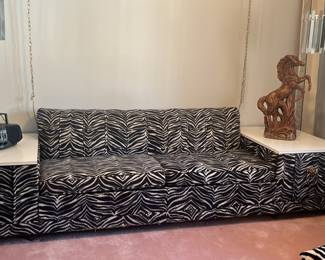 11 feet long by 32 inch deep Vintage zebra Castro convertible sofa bed with built-in end tables. The tops of the tables are bright white for Maika. The hardware on the pullout drawers is the iconic brass lion door knocker style. And of course, the drawers are lined in fabulous red flocking. It is truly an unusual piece and was custom-made in the late 60s early 70s. 