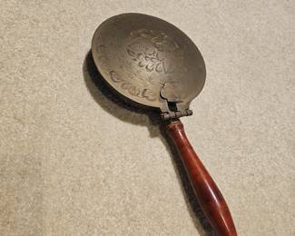 Vintage brass silent butler crumb catcher with floral embossing and wooden handle.