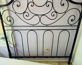Elegant black wrought iron headboard with intricate scroll design.
