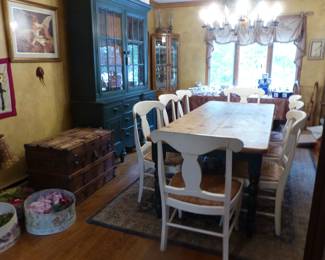 Rustic farmhouse dining table with 8 chairs, painted green breakfront, curio cabinets, antique trunks