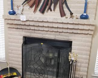 Fireplace screen and tools plus metal artwork and items on mantle.