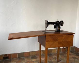 1920s Singer sewing machine folds down in the cabinet.