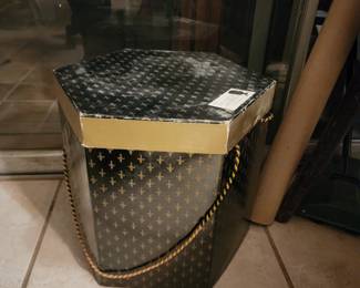 vintage black and gold hexagonal hat box with a fleur-de-lis pattern. 