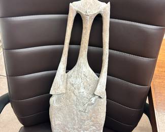 This is a stylized, textured sculpture, depicting a tall elongated, female figure resembling the artistic style of Pierre Yermia.