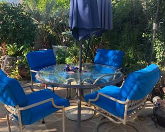 Outdoor Dining Table with Four Chairs. Blue Sunbrella Umbrellas and Stands Sold Separately.