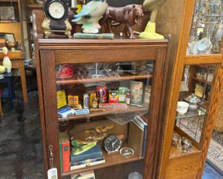 antique oak book shelf with door, carved wooden lion, duck figurine, vintage clock and blow dryer, tins