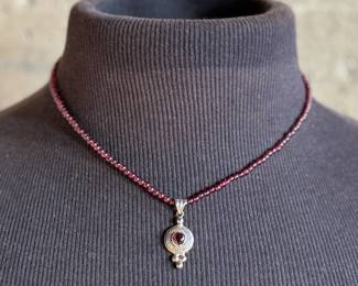 This lot features a vintage garnet beaded necklace with a sterling silver pendant containing a single garnet stone. This necklace measures, 17”.

