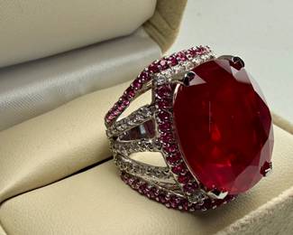 This lot features a statement piece! A large 30+ carat oval ruby cocktail ring set in sterling silver with diamonds and sapphires. This ring comes in a size 5.5 with a total approx. weight of 14.64 grams.

