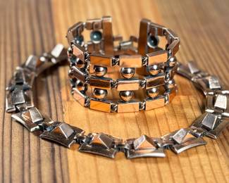 This lot features a necklace and bracelet by Renoir Copper. The necklace measures, 15” and the bracelet, 6.5”. Renoir copper jewelry is a highly collectible mid-century costume line produced by Jerry Fels in California from 1946 to 1964. Renowned for its abstract, modernist, and Arts & Crafts-inspired designs, the company specialized in solid, hand-hammered copper, frequently featuring bold, minimalist forms. 

