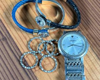 This lot features a collection of Brighton jewelry including scalloped stack rings, leather braided bracelets, and more. Founded in 1991 by Jerry and Terri Kohl, Brighton is a family-owned, Los Angeles-based design house specializing in high-quality, artisan-crafted, and often heart-themed accessories. Originating from a background in leather goods (starting in 1972), the brand blossomed into a premier jewelry maker known for its in-house design, intricate metalwork, and nickel-free materials.

