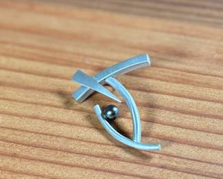 This lot features a rare modernist pin with a satin sterling silver finish and a genuine pearl. Total approx. weight of 5.88 grams.

