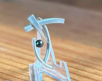 This lot features a rare modernist pin with a satin sterling silver finish and a genuine pearl. Total approx. weight of 5.88 grams.

