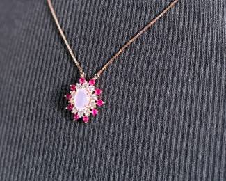 This lot features a stunning rose gold colored silver quartz and ruby pendant necklace with a chain extender. Measures at 20”, marked 925, and has a total approx. weight of 4.59 grams.


