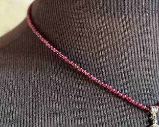 This lot features a vintage garnet beaded necklace with a sterling silver pendant containing a single garnet stone. This necklace measures, 17”.

