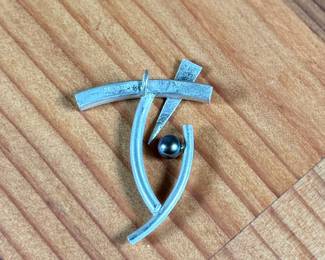 This lot features a rare modernist pin with a satin sterling silver finish and a genuine pearl. Total approx. weight of 5.88 grams.

