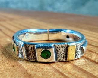 This lot features a hand made ring by maker, Armstrong. The ring is crafted from sterling silver and 22k gold. This ring comes in a size 10, a broken band as shown in photos, and a total approx. weight of 5.66 grams.

