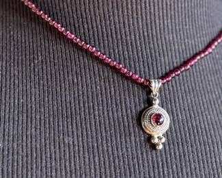This lot features a vintage garnet beaded necklace with a sterling silver pendant containing a single garnet stone. This necklace measures, 17”.

