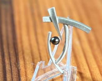 This lot features a rare modernist pin with a satin sterling silver finish and a genuine pearl. Total approx. weight of 5.88 grams.

