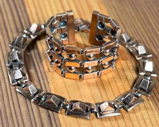 This lot features a necklace and bracelet by Renoir Copper. The necklace measures, 15” and the bracelet, 6.5”. Renoir copper jewelry is a highly collectible mid-century costume line produced by Jerry Fels in California from 1946 to 1964. Renowned for its abstract, modernist, and Arts & Crafts-inspired designs, the company specialized in solid, hand-hammered copper, frequently featuring bold, minimalist forms. 

