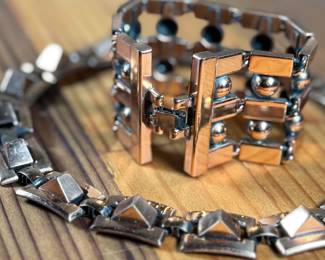 This lot features a necklace and bracelet by Renoir Copper. The necklace measures, 15” and the bracelet, 6.5”. Renoir copper jewelry is a highly collectible mid-century costume line produced by Jerry Fels in California from 1946 to 1964. Renowned for its abstract, modernist, and Arts & Crafts-inspired designs, the company specialized in solid, hand-hammered copper, frequently featuring bold, minimalist forms. 

