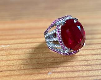 This lot features a statement piece! A large 30+ carat oval ruby cocktail ring set in sterling silver with diamonds and sapphires. This ring comes in a size 5.5 with a total approx. weight of 14.64 grams.

