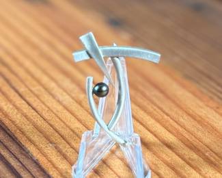 This lot features a rare modernist pin with a satin sterling silver finish and a genuine pearl. Total approx. weight of 5.88 grams.

