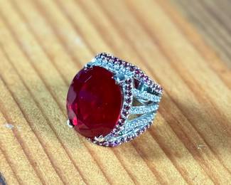 This lot features a statement piece! A large 30+ carat oval ruby cocktail ring set in sterling silver with diamonds and sapphires. This ring comes in a size 5.5 with a total approx. weight of 14.64 grams.

