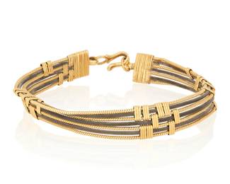 1065
A 20k Gold and Elephant Hair Bracelet
Featuring three rows of elephant hairs between four rows of twisted gold

Measures: 6 3/4 in.
11.9 grams gross
Estimate: $1,200 - $1,800